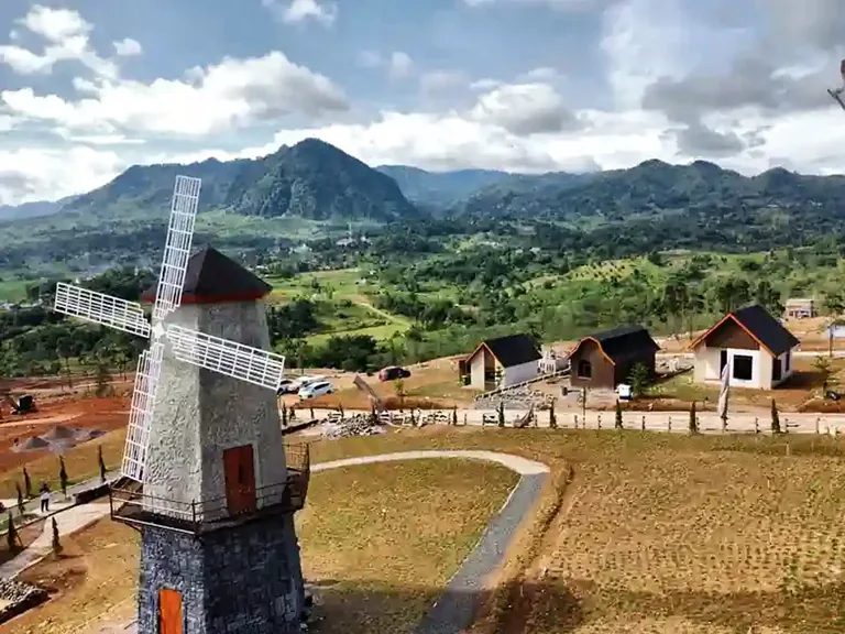 Landmark kincir angin dan bangunan villa dengan latar pegunungan pada dokumentasi The Hanjawong Villas.